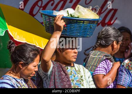 A young Tzutujil Mayan woman in traditional dress carries her purchases on her head in the weekly market in Santiago Atitlan, Guatemala. Stock Photo