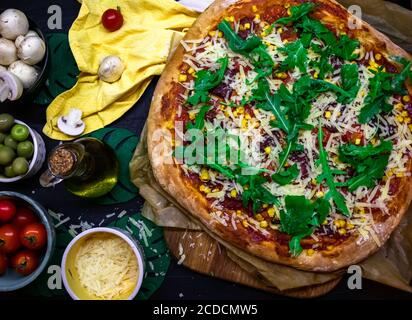 Delicious homemade pizza freshly baked flat lay with colorful ingredients on table Stock Photo