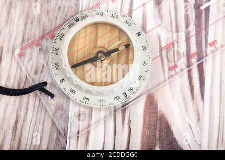 old transparent plastic sport compass with azimuth measurement on wooden background Stock Photo