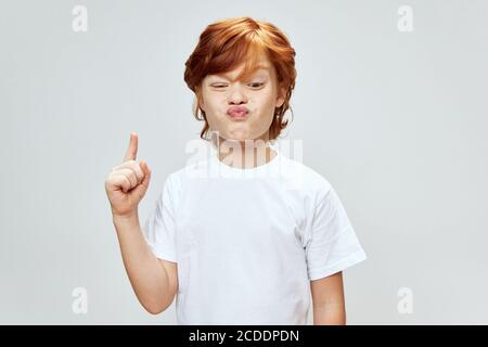 Expressive red-haired boy shows his index finger up Copy space Stock Photo