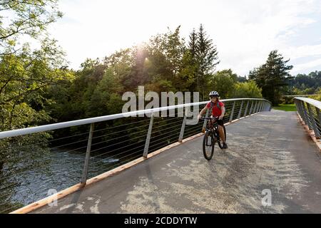 Young boy cycling across a footbridge Stock Photo