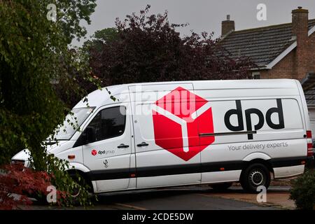 A DPD delivery van parked on a driveway while the driver delivers a parcel. Stock Photo