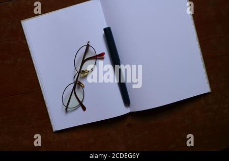 Closeup blank notebook, eyeglasses and pen placed on wooden table Stock Photo