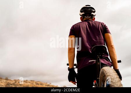 Detail of cyclist man with mountain bike on outdoor. Portrait of a man on a mountain bike in the mountains in cloudy weather. Mountain bike and extrem Stock Photo