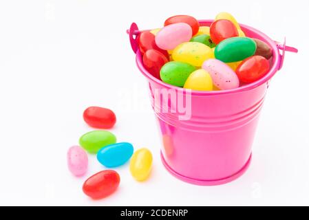 Colorful candies in pink bucket on a white background and near the bucket Stock Photo