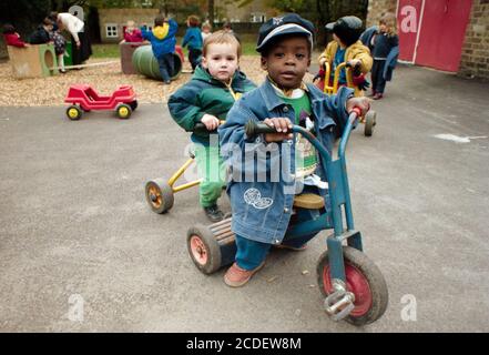 Two boys riding tricycles in the outdoor area at West Hampstead Pre-School in London NW6. 25 October 1993. Photo: Neil Turner Stock Photo