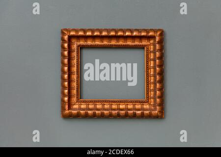 Ornate gold empty frame hanging centered on a green wall with copyspace for an artwork, picture or painting Stock Photo