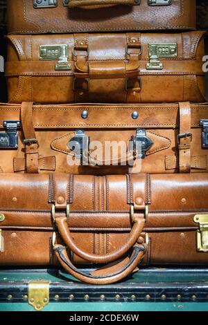 Stack of vintage brown leather suitcases on an old green trunk in a partial close up view conceptual of travel or the Grand Tour Stock Photo
