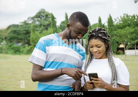Cute African couple looking at their phone and smiling Stock Photo