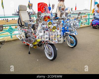 Vintage motor scooter motorbikes with headlamps in Brighton from the Mods and Rockers era, with multiple headlights and wing mirrors Stock Photo