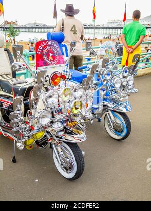 Vintage motor scooter motorbikes with headlamps in Brighton from the Mods and Rockers era, with multiple headlights and wing mirrors Stock Photo