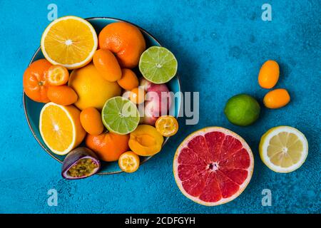 Summer and citrus fruits in bowl on blue background.  Healthy eating concept. Stock Photo