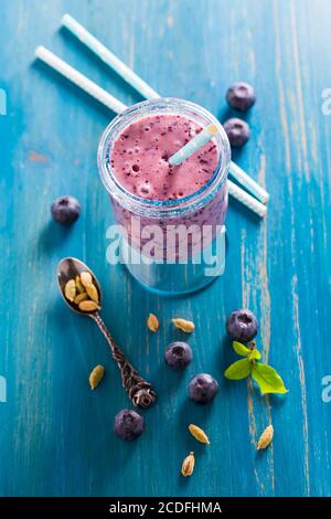 Healthy blueberry lassi or smoothie drink with cardamom on blue wooden background Stock Photo