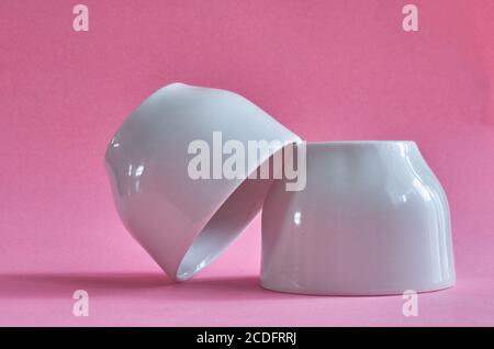 Two white ceramic cups without handles on a pink background Stock Photo