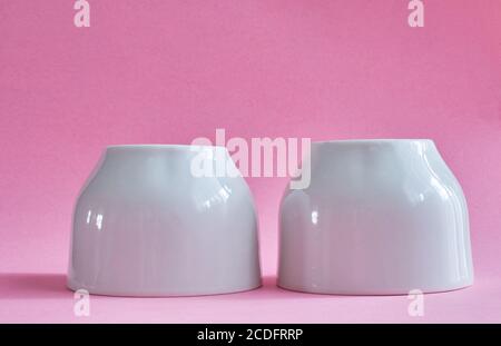 Two white ceramic cups without handles on a pink background Stock Photo