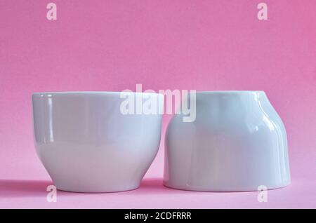 Two white ceramic cups without handles on a pink background Stock Photo