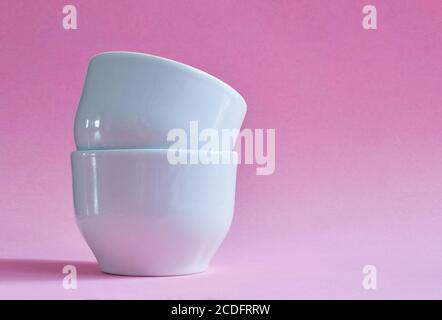 Two white ceramic cups without handles on a pink background Stock Photo