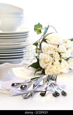 White plates stacked with utencils and roses Stock Photo