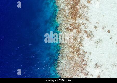 Cropped top above high angle aerial drone view of pure blue ocean water washing seashore stones coral reef wild luxurious destination tour hot sale Stock Photo