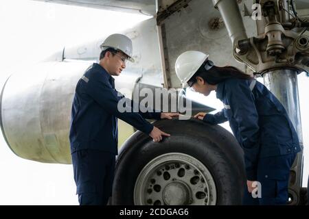 Asian man and woman engineer maintenance airplane team repairs, fixes, modernization and renovation in front airplane from  in airport. Stock Photo