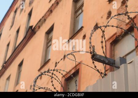 Barbed wire fence wall on security building background. Stock Photo