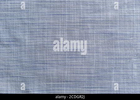 The texture of the white and blue fabric with small stripes with delicate creases - a close-up of a fragment of a linen shirt Stock Photo