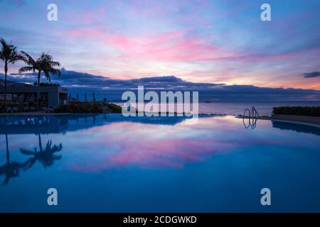 Portugal, Madeira, Funchal, Sunrise reflecting in infinity pool at Pestana Casino Hotel Stock Photo