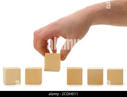 The hand establishes a wooden cube in row Stock Photo