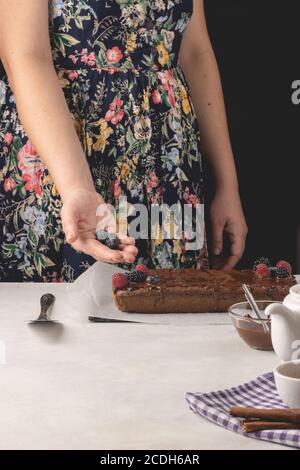 Woman holding blueberries over delicious cinnamon cake placed on white background. Stock Photo