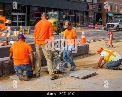 Construction workers using electric suction lifter to place pavement blocks on Lake Street Reconstruction Project. Oak Park, Illinois. Stock Photo