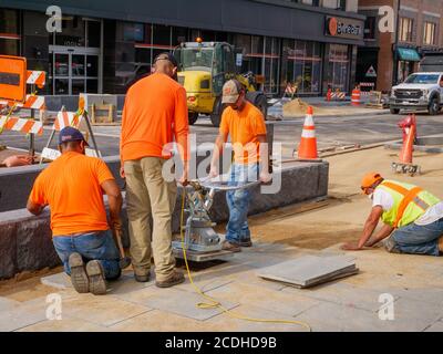 Construction workers using electric suction lifter to place pavement blocks on Lake Street Reconstruction Project. Oak Park, Illinois. Stock Photo