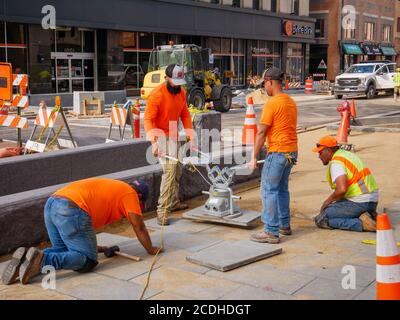Construction workers using electric suction lifter to place pavement blocks on Lake Street Reconstruction Project. Oak Park, Illinois. Stock Photo