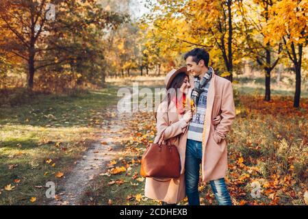 Stylish couple in love walks in autumn park among colorful trees. Man and woman hugging outdoors at sunset Stock Photo
