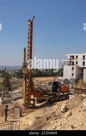 Mevasseret Zion, Israel - August 13th, 2020: Construction workers digging foundations on a residential project, using a heavy crawler drilling machine Stock Photo