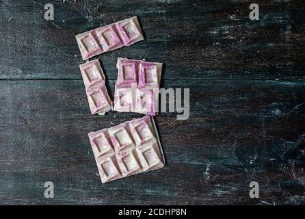 Handmade white chocolate with nuts and fruits broken into pieces. Dark wooden background. Stock Photo