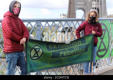 Menai Bridge, Anglesey, 28 August 2020. Extinction Rebellion youth protestors face the bank holiday traffic heading into Anglesey with banners highlighting climate change and calling for action to protect their future Credit: Denise Laura Baker/Alamy Live News Stock Photo