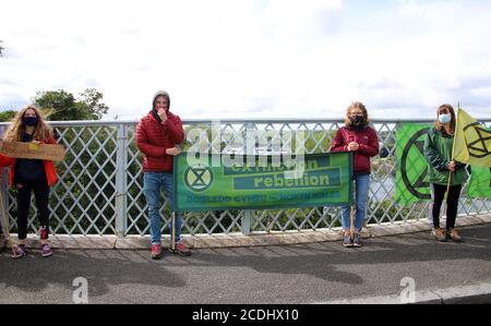 Menai Bridge, Anglesey, 28 August 2020. Extinction Rebellion youth protestors face the bank holiday traffic heading into Anglesey with banners highlighting climate change and calling for action to protect their future Credit: Denise Laura Baker/Alamy Live News Stock Photo