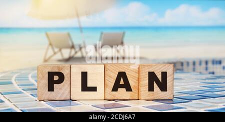 Plan word made with building blocks on relaxed beach background. Sun umbrella and sea. Business investment concept Stock Photo