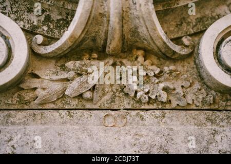 Wedding rings of the bride and groom on a stone texture with patterns. Stock Photo