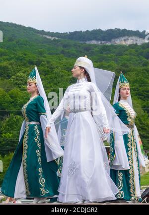 Adygea, RUSSIA - JULY 25 2015: Female dancers in traditional costumes Circassian green hills in the background. Ethnic festival in the foothills of th Stock Photo