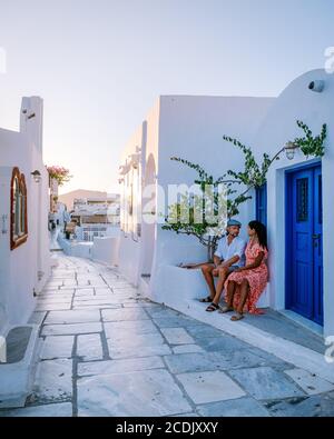 Santorini Greece, young couple on luxury vacation at the Island of Santorini watching sunrise by the blue dome church and whitewashed village of Oia Stock Photo