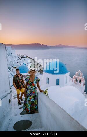 Santorini Greece, young couple on luxury vacation at the Island of Santorini watching sunrise by the blue dome church and whitewashed village of Oia Stock Photo