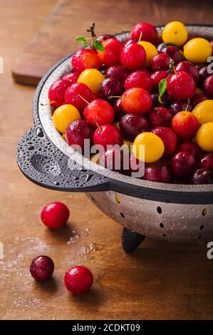 Fresh plums in a colander on a wooden table Stock Photo