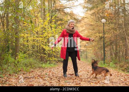 Smiling middle aged woman in the forest with her dog Stock Photo