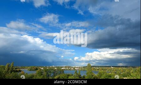 Blue sky with cumulonimbus over the water. Beautiful landscape at the countryside. Sunny day with view on a lake.Cloudy weather turning rainy. Stock Photo
