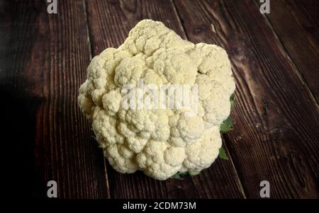 Closeup on whole white raw cauliflower vegetable on dark wooden board Stock Photo