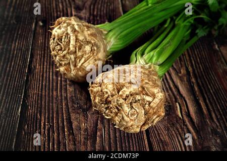 Celery root with green leaves on dark wooden board Stock Photo