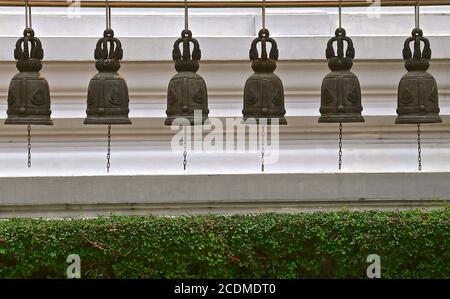 A row of six cast iron decorative temple bells in a buddhist temple in Asia. Stock Photo