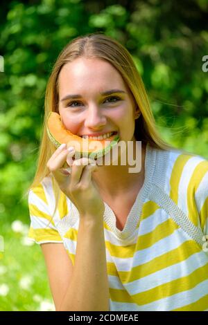 Portrait young blonde woman, biting into a melon, fruit, summer, Bavaria, Germany Stock Photo
