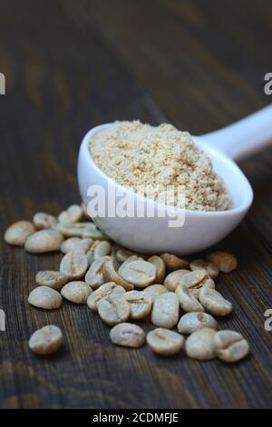 Green coffee beans and unroasted coffee powder in spoon, Germany Stock Photo